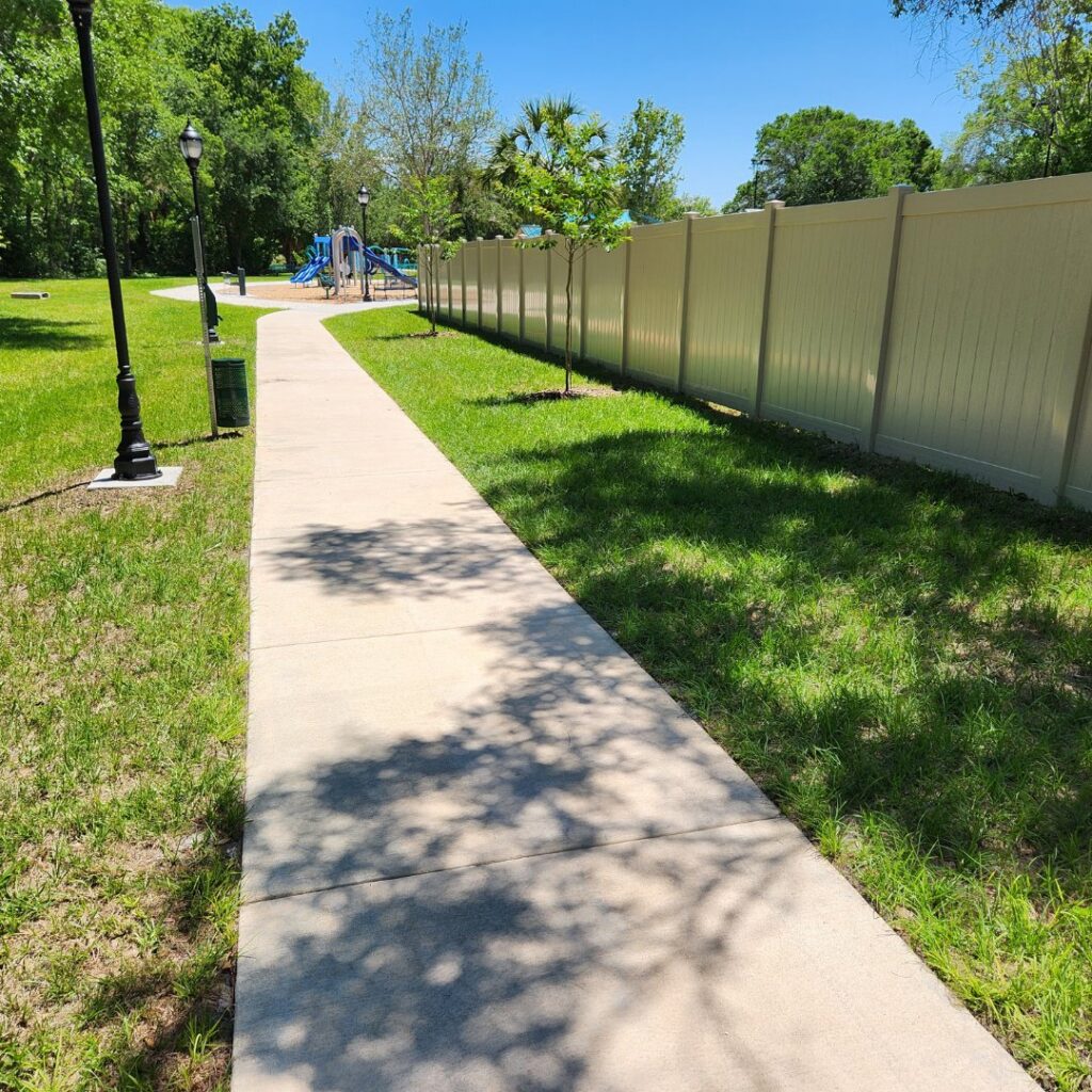 A white vinyl privacy fence installed next to a playground by Keeler Fence in New Port Richey, FL.