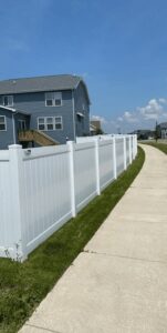 A long white vinyl privacy fence installed along a sidewalk next to a house by Badger Vinyl Products in Madison, WI.