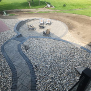 Wide aerial view of a paver patio with fire pit and seating by Great Plains Remodeling and Handyman Services in Mitchell, SD.