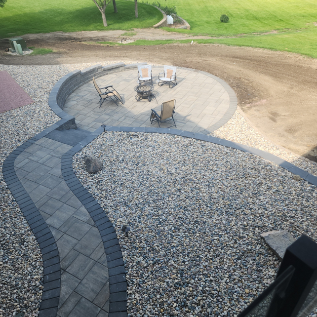 Wide aerial view of a paver patio with fire pit and seating by Great Plains Remodeling and Handyman Services in Mitchell, SD.