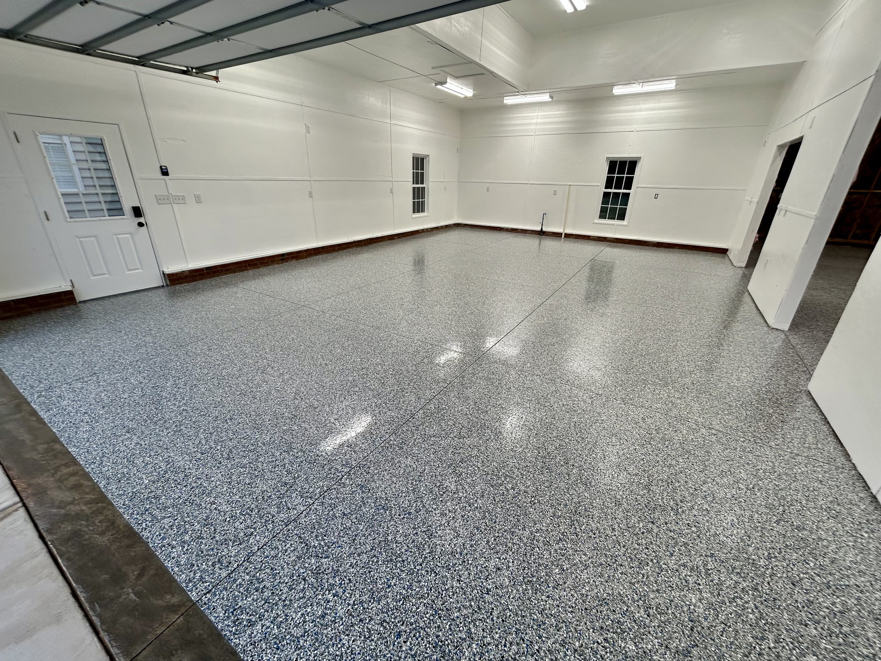 A wide garage interior featuring a finished speckled epoxy floor by Garage Upgrade Pros in Fort Mill, SC.