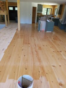Wide plank wood floor being finished with a roller and bucket by Robert C. Mihaich Wood Flooring in Worcester, MA.