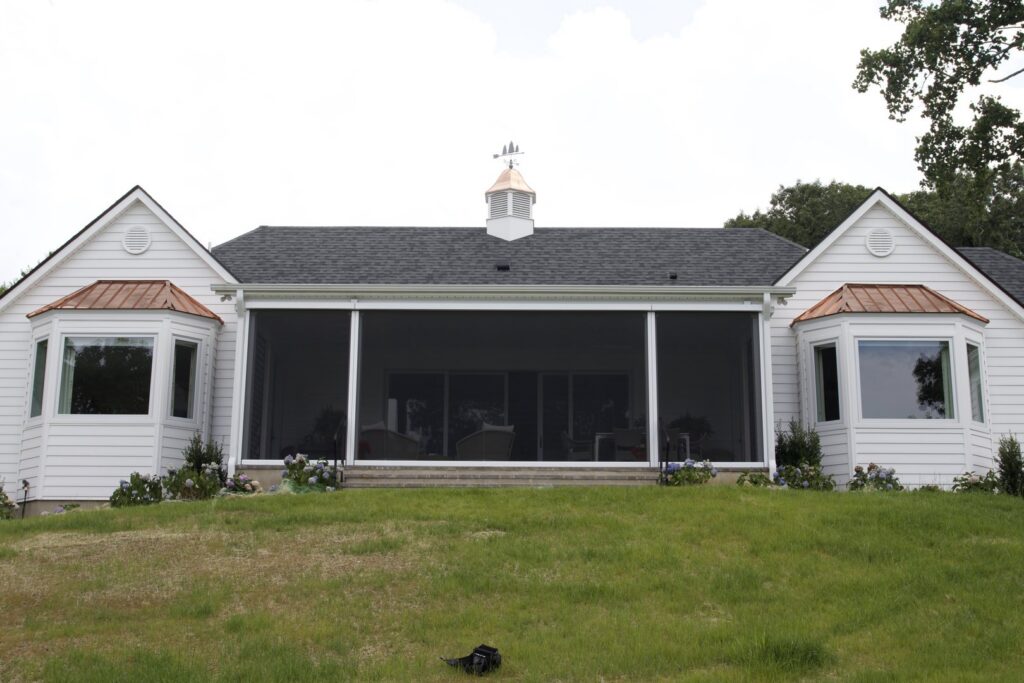 A large house featuring a wide, inviting screened porch flanked by elegant bay windows, built by Screen Enc in Denver, NC