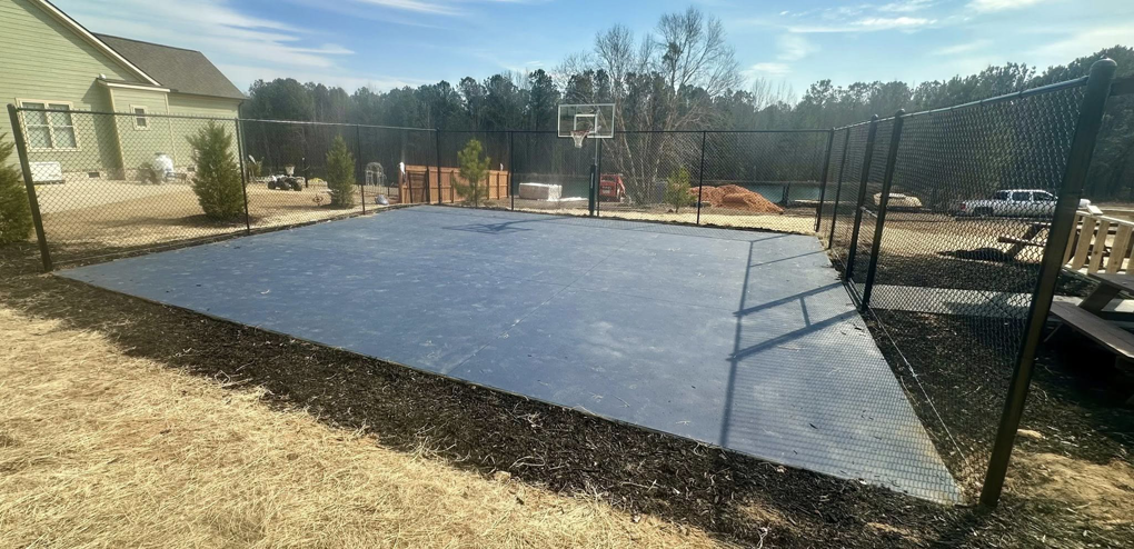 A wide view of a newly constructed outdoor basketball court with a chain-link fence by Legacy Fence, LLC in Aiken, SC.