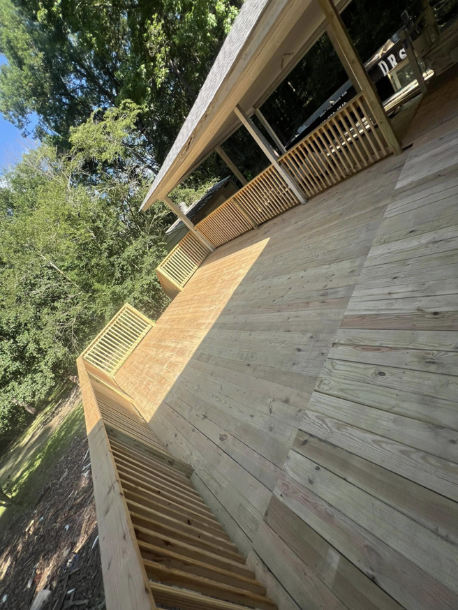 A wide view of a beautifully completed wooden deck with railings and a covered area by JD Handyman service LLC in Miami, FL.