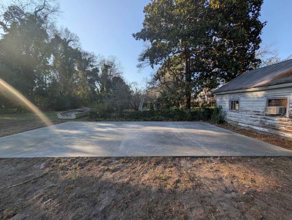 A wide view of a newly poured concrete pad in a backyard, completed by Allen's Concrete Finishing in Rock Hill, SC.