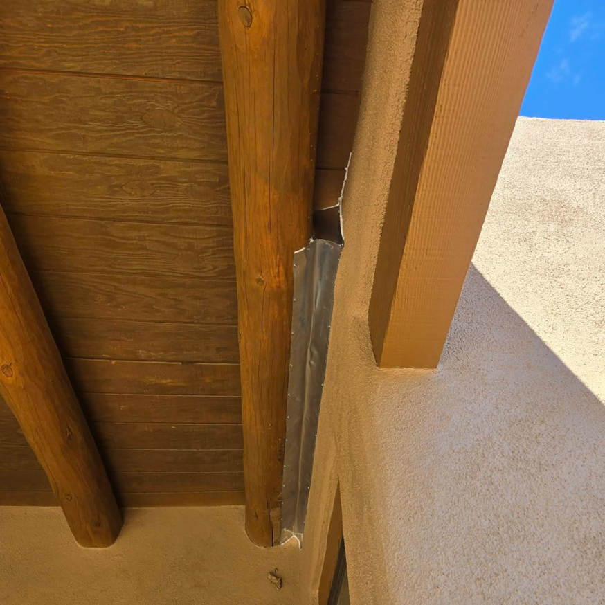 Wildlife exclusion flashing installed between a wooden beam and stucco wall by Sonoran Wildlife Services in Tucson, AZ.