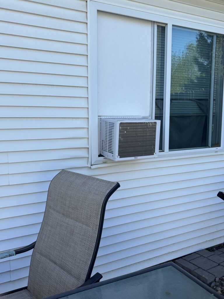 A window air conditioning unit professionally installed in a window of a house by Amazing Handyman Services in West Fargo, ND