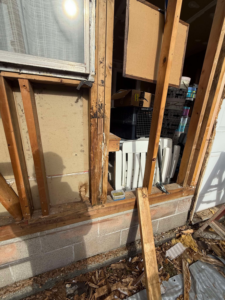 Exposed wooden window frame and studs during repair or demolition work by CJ Hansen Construction in North Bend, OR.