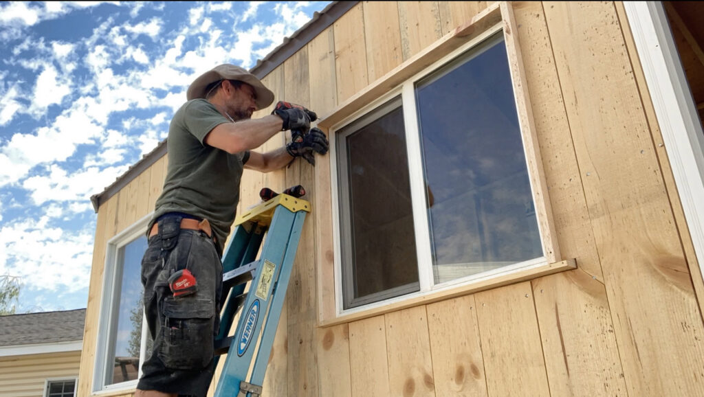 A handyman installing a window or exterior trim on a wooden building by Top Shelf Handyman Pros in Post Falls, ID