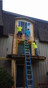 Workers on scaffolding installing a new window on a building by CMFM Construction in Columbia, MO