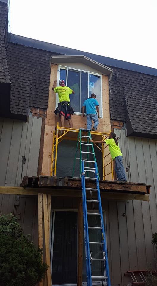 Workers on scaffolding installing a new window on a building by CMFM Construction in Columbia, MO