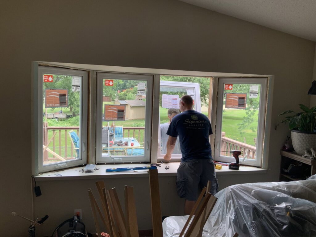 A handyman from Nordic Construction installing a new window inside a home in Plymouth, MN.