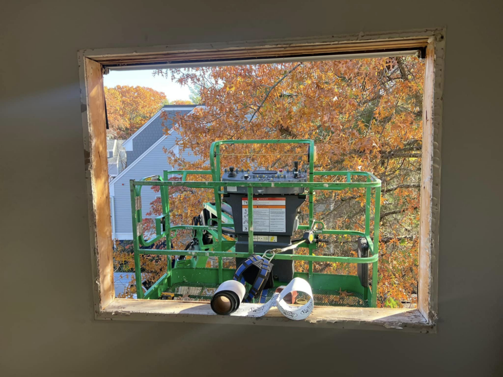 Window installation in progress with a construction lift visible outside, handled by Fox Solutions Corp in Worcester, MA