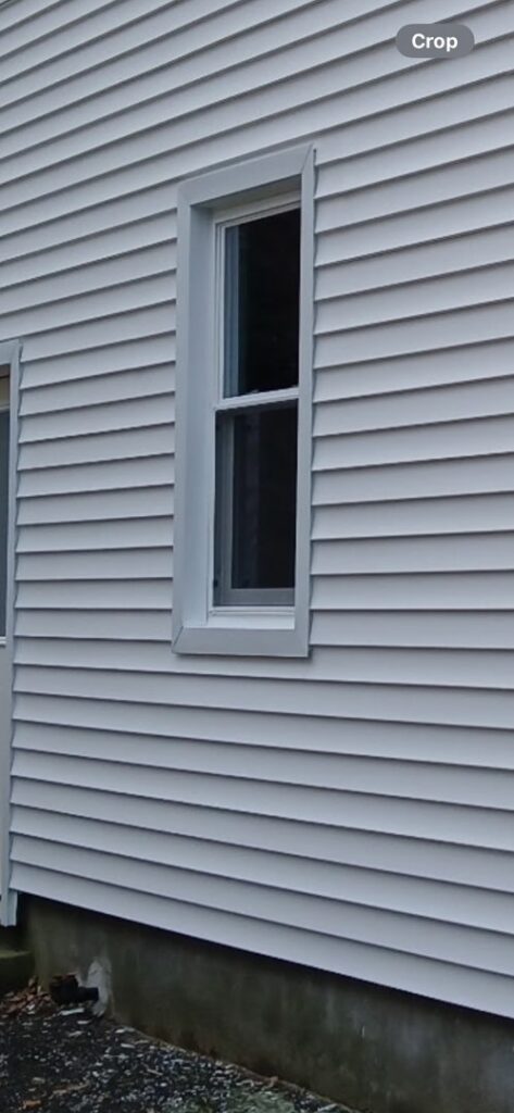 A newly installed white window and siding on a house by Class General Contracting in West Springfield, MA.