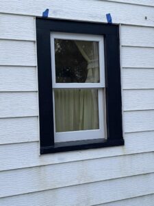 A newly installed window with black trim on a white-sided house by S-Squared Construction in Madison, WI.