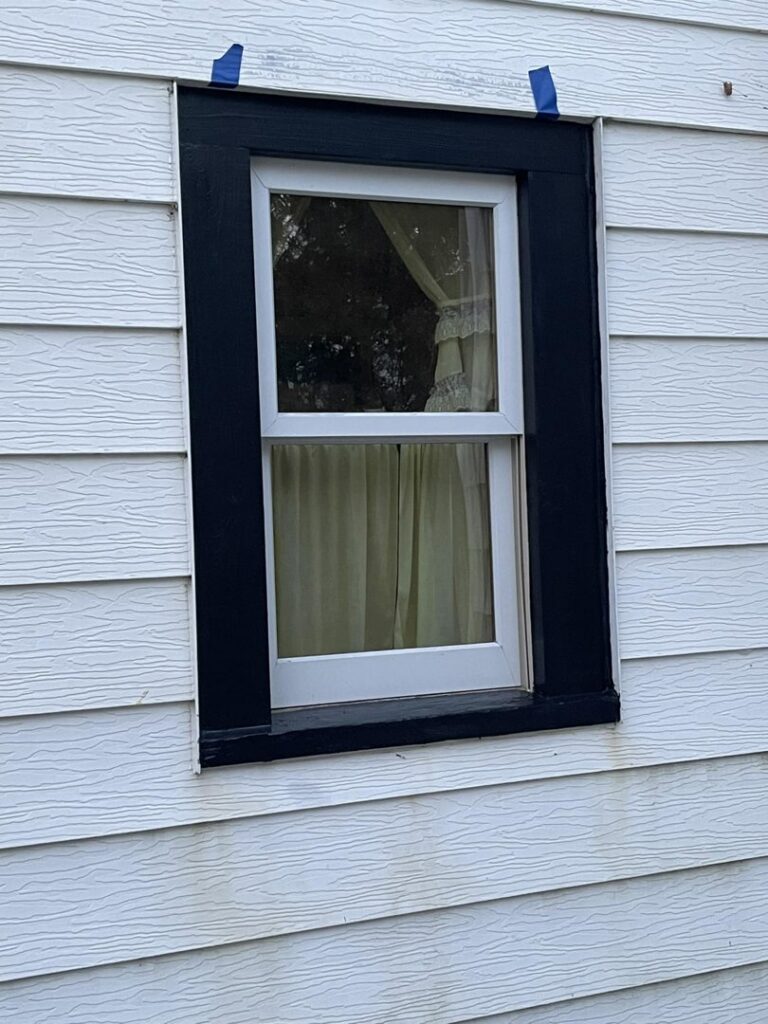 A newly installed window with black trim on a white-sided house by S-Squared Construction in Madison, WI.