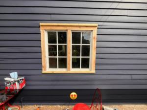 Window trim installation with tools visible on a blue-sided house by McDonald Residential Contracting in Ames, IA.