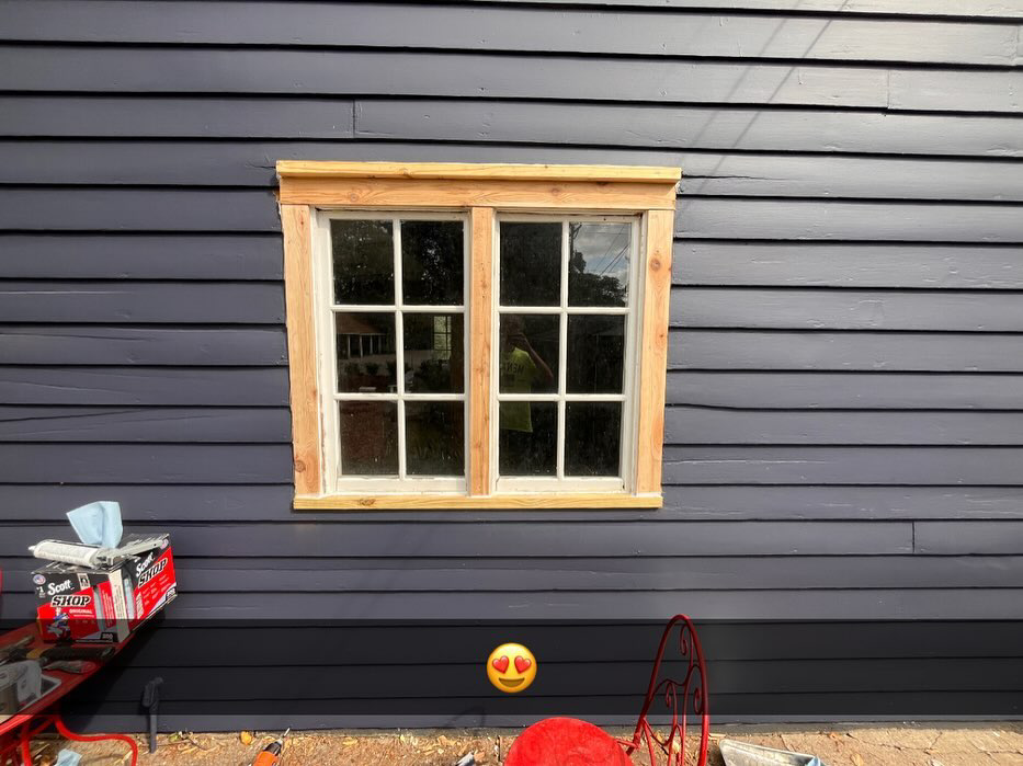 Window trim installation with tools visible on a blue-sided house by McDonald Residential Contracting in Ames, IA.