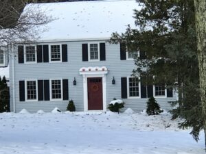 A house with new light blue siding, black shutters, and a red front door, completed by Bartlett Brainard Products Co. in West Hartford, CT.