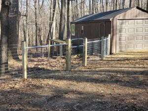 A wire mesh fence with wooden posts and a gate installed by Quality Fence & Deck Co. in Frederick, MD.