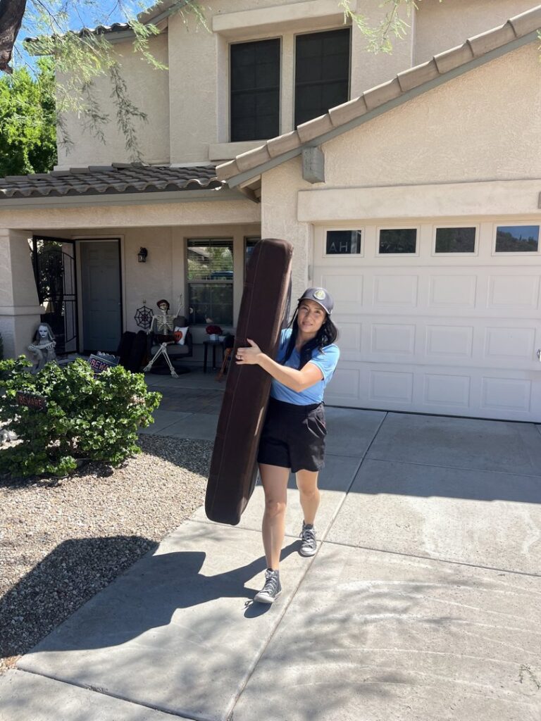 A woman carrying a piece of furniture for Happy Hippo Junk Removal in Scottsdale, AZ.