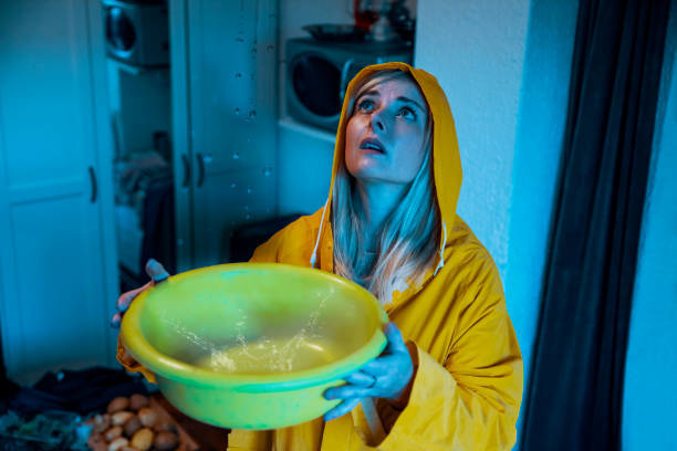 A woman catching water from a ceiling leak, a common home repair handled by B&S Home Improvement in Evansville, IN.