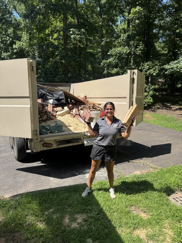 A Dumpzilla team member loading bricks and construction debris into a dump trailer in Raleigh, NC.