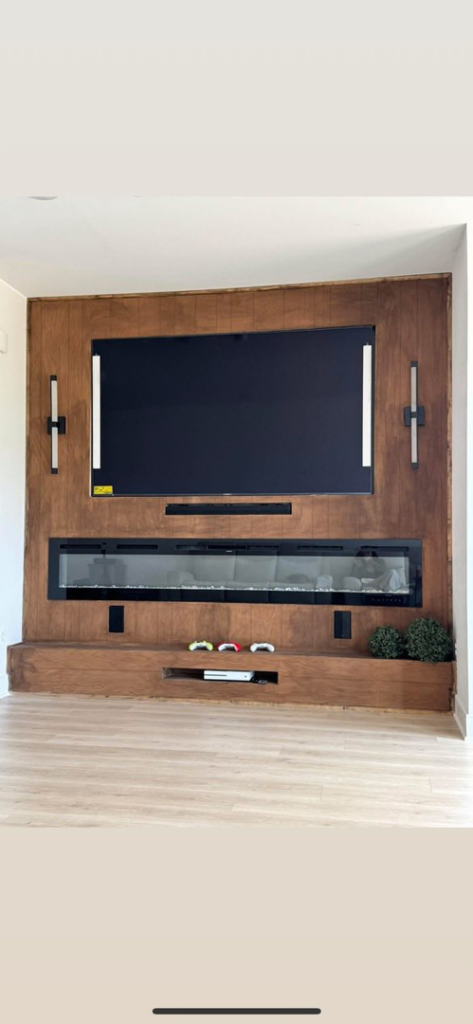 A modern living room featuring a custom wood accent wall with integrated TV and electric fireplace by Wareham Home Improvements in Frederick, MD.