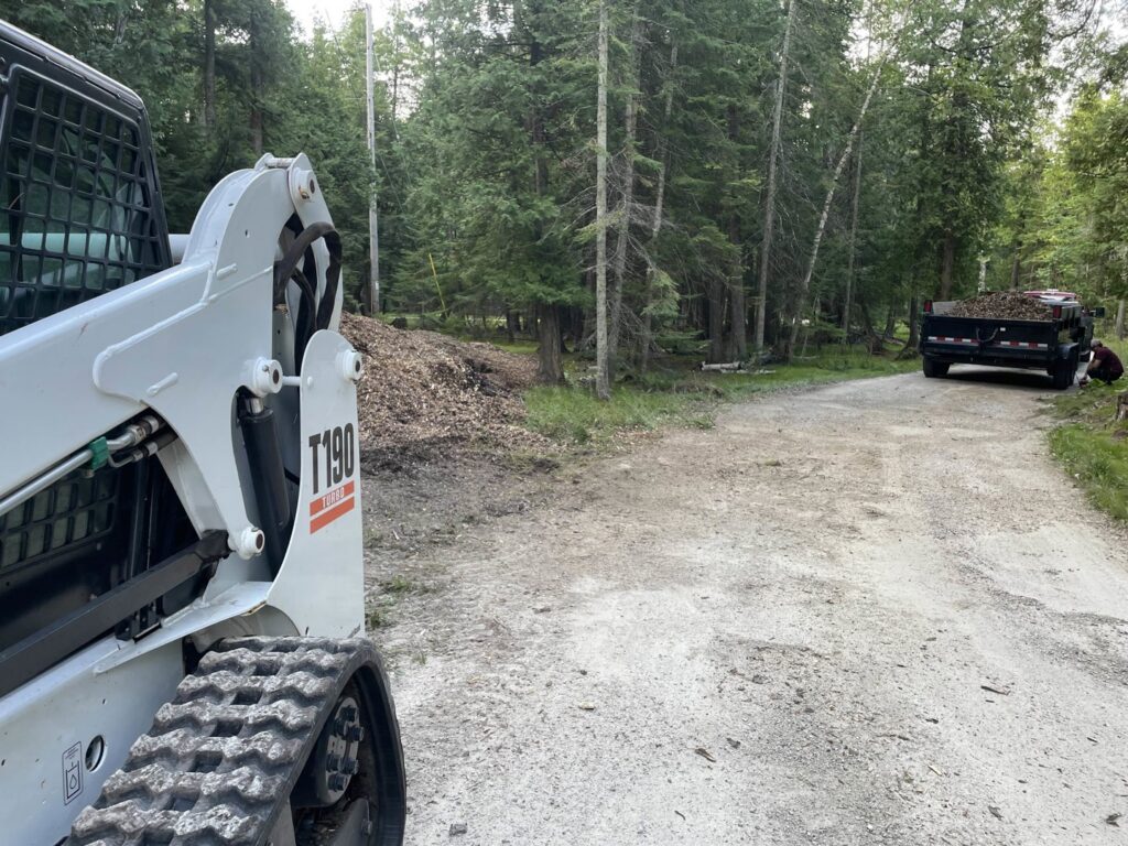 Wood chip and debris removal with a skid steer and dump trailer by A&A Property Renovations LLC in Green Bay, WI.