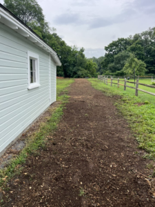 A freshly laid wood chip path next to a light-colored building, showing work by Green Mtn Stump Grinding in Montpelier, VT.