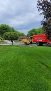 A wood chipper and a branded chip truck from Clyde's Tree Service in Indianapolis, IN, used for tree debris removal.