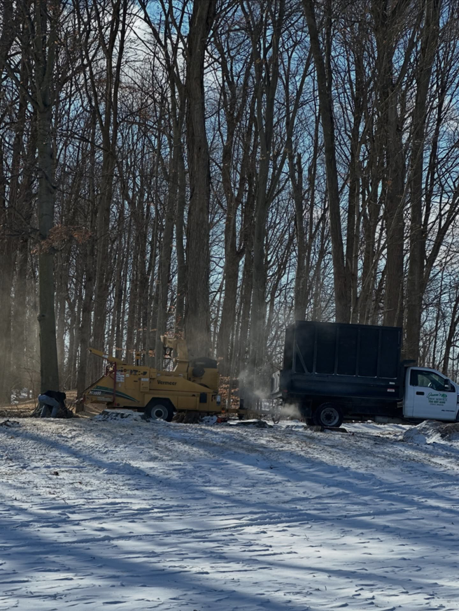 A wood chipper and dump truck used for tree removal and clearing by Jason's Tree Service Llc. in Garden City, MI.