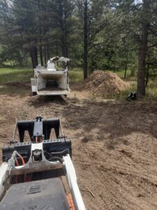 A wood chipper and skid steer used for efficient tree service cleanup by Lind Legacy Tree Service in Colorado Springs, CO