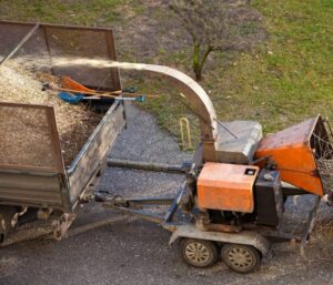 A wood chipper actively chipping tree branches into a trailer for debris removal by Pittsburgh Tree Trimming & Removal Service in Pittsburgh, PA.