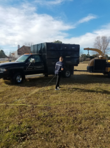 A wood chipper and dump truck used for tree debris removal by Buckeye Tree Services Inc. in Papillion, NE, parked in a grassy area.