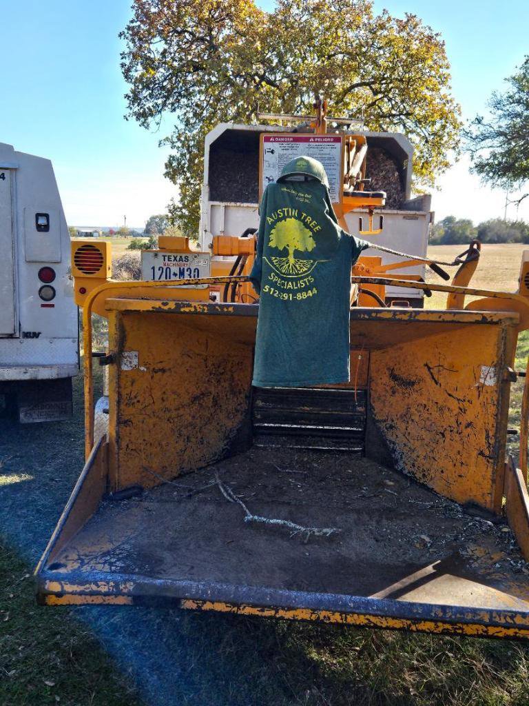 A wood chipper with an Austin Tree Specialists shirt, representing tree service equipment in Austin, TX.