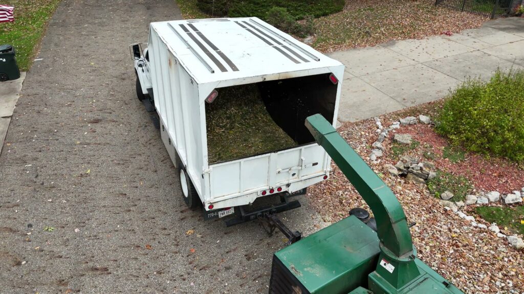 A wood chipper loading tree debris into a large dump truck during a cleanup job by Kingdom Tree Company in North Canton, OH.
