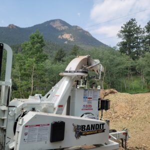 A powerful wood chipper used by Lind Legacy Tree Service with a scenic mountain background in Colorado Springs, CO