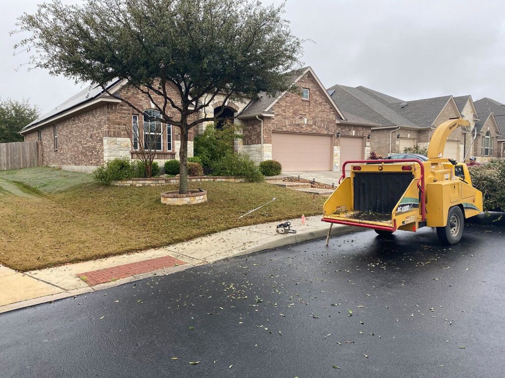 A wood chipper parked on a residential street with leaves on the ground, used by Luna's Tree Service in San Antonio, TX.