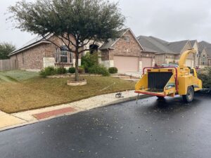 A wood chipper parked on a residential street with leaves on the ground, used by Luna's Tree Service in San Antonio, TX.