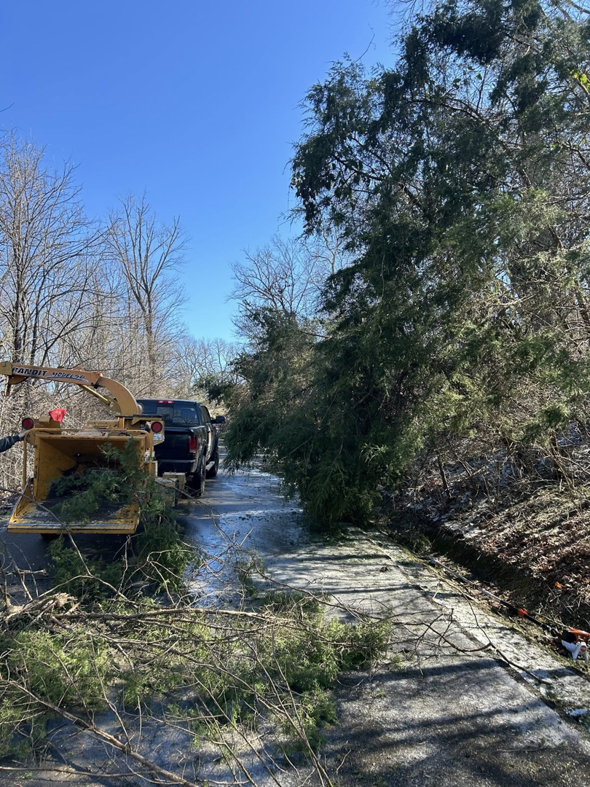 A wood chipper processing tree branches on the side of a road for B&D Tree Service and Landscaping in Dallas, TX.