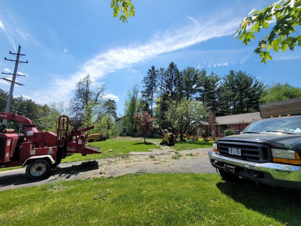 A wood chipper, dump truck, and stump grinder on a driveway with tree debris after a service by Dave's Tree & Stump Removal LLC in Parma, OH.