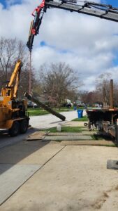 A crane feeding a large log into a wood chipper during tree removal by Ecotree Services LLC in Lorain, OH.