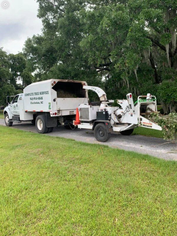 A wood chipper attached to a Complete Tree Service, LLC truck, processing branches after a tree service job in Charleston, SC.