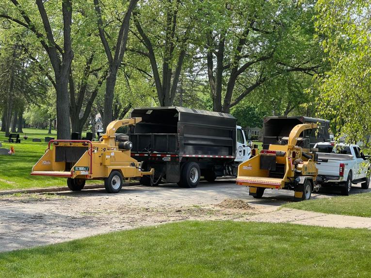 Two wood chippers and dump trucks are parked, ready for debris removal by Canopy Cops Tree Service LLC in Appleton, WI.