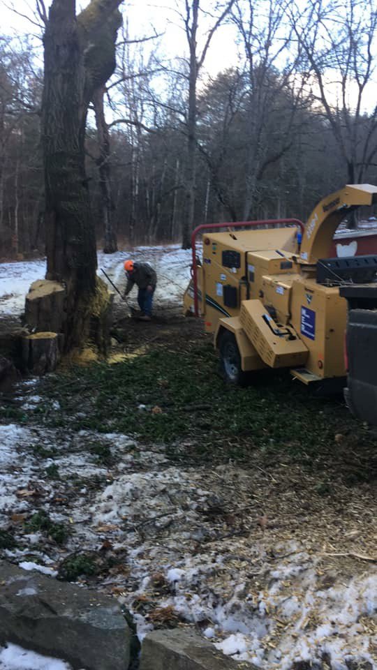A tree surgeon from Bryan McFadden LLC Tree Surgeon operating a wood chipper during a winter job in Auburn, ME.
