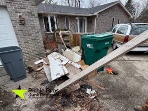 A pile of wood debris and various junk items outside a house, ready for removal by Richie Bros Junk Removal in Urbandale, IA.