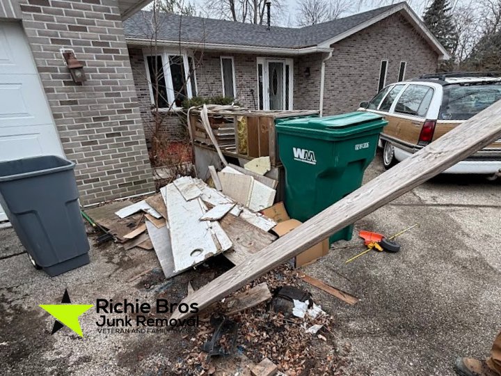 A pile of wood debris and various junk items outside a house, ready for removal by Richie Bros Junk Removal in Urbandale, IA.
