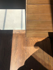 A close-up of a seamless transition between wood flooring, tile, and wood wall paneling by Blackhawk Floors, Inc. in Scottsdale, AZ